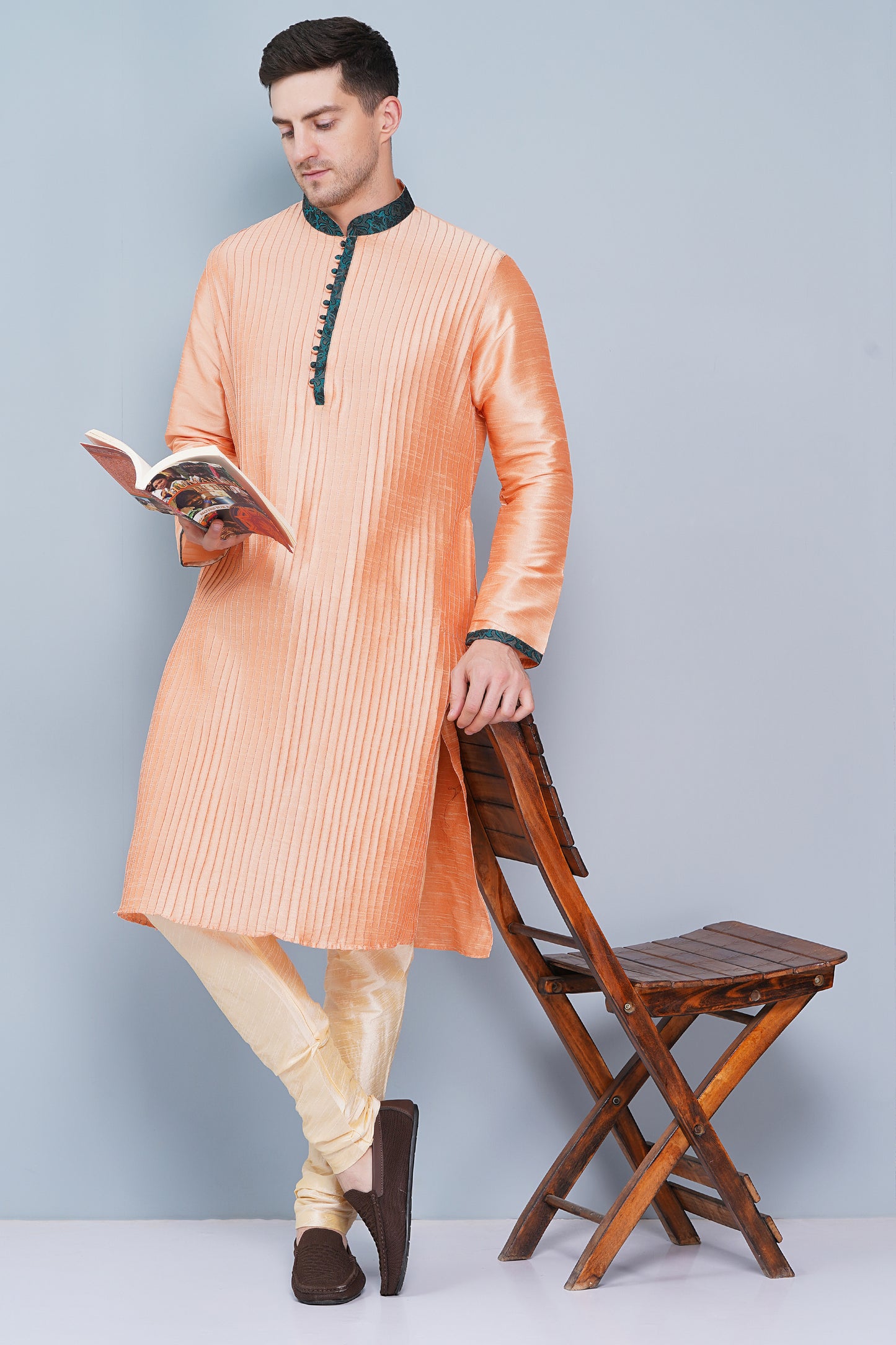 Men Peach color traditional Kurta with green accent on collar, placket and cuffs, full length, boondi button with loops closure, one fourth placket, full sleeves, mandarin collar, side pockets on Kurta with Off-white or cream color chudidar pajama. Perfect traditional wear for family special occasions, wedding, house warming, casual wear