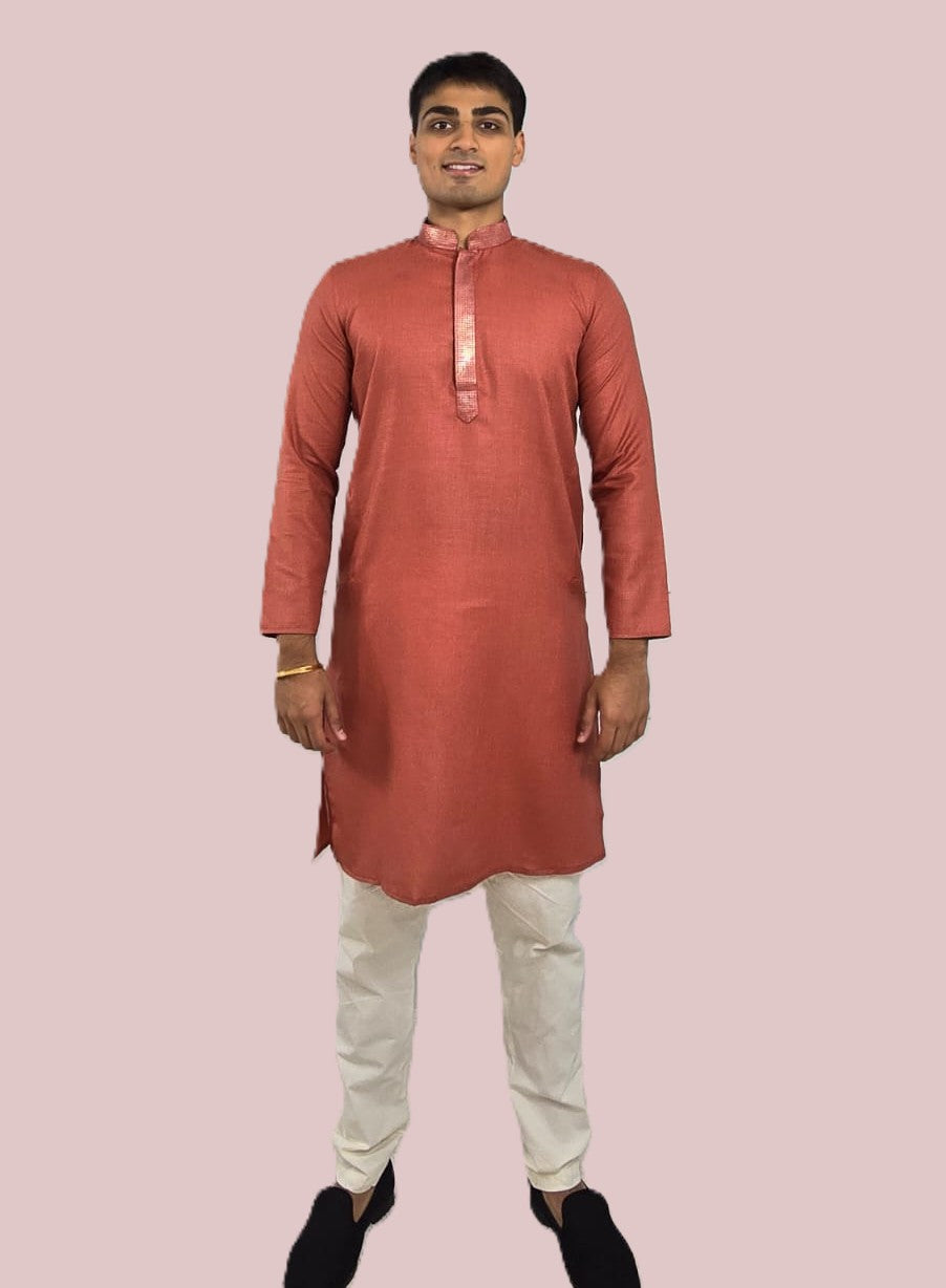 Men's rust or deep carrot color kurta with embroidered neckline paired with white churidar, mandarin collar, side pockets, full sleeves - premium Indian formal wear for weddings and special occasions