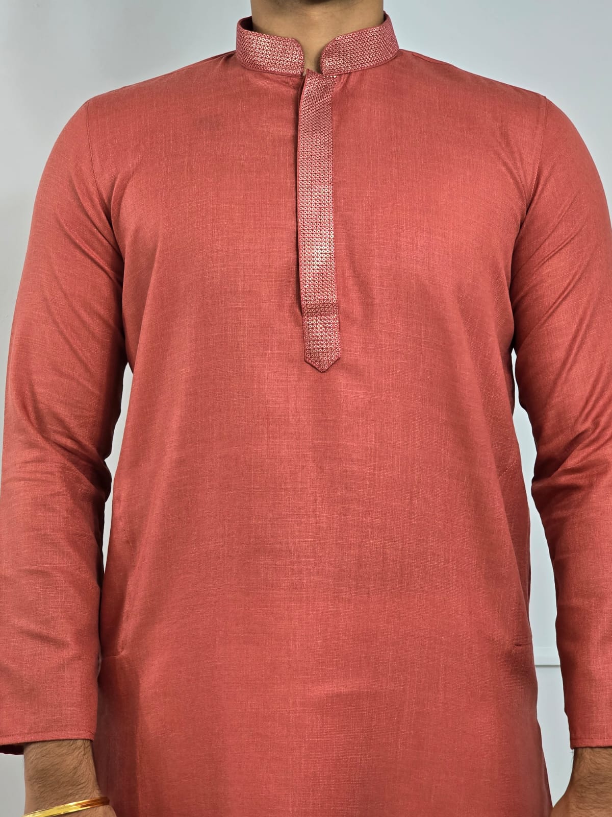 Men's rust or deep carrot color kurta with embroidered neckline paired with white churidar, mandarin collar, side pockets, full sleeves - premium Indian formal wear for weddings and special occasions