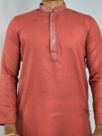 Men's rust or deep carrot color kurta with embroidered neckline paired with white churidar, mandarin collar, side pockets, full sleeves - premium Indian formal wear for weddings and special occasions