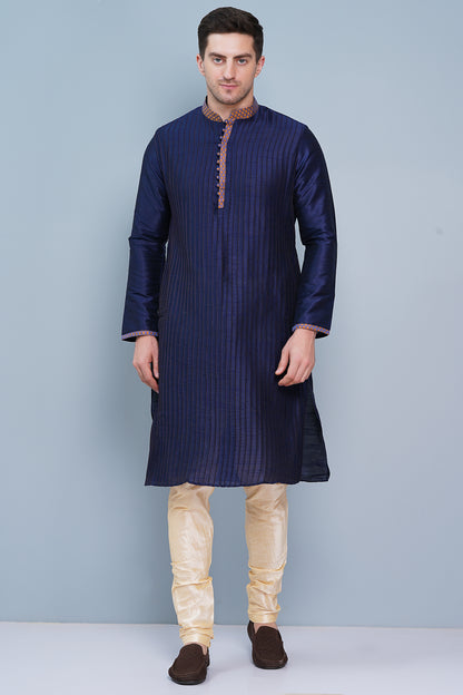 Men Navy Blue traditional Kurta with orange accent  on collar, placket and cuffs, full length, boondi button with loops closure, one fourth placket, full sleeves, mandarin collar, side pockets on Kurta with Off-white or cream color chudidar pajama. Perfect traditional wear for family special occasions, wedding, house warming, casual wear