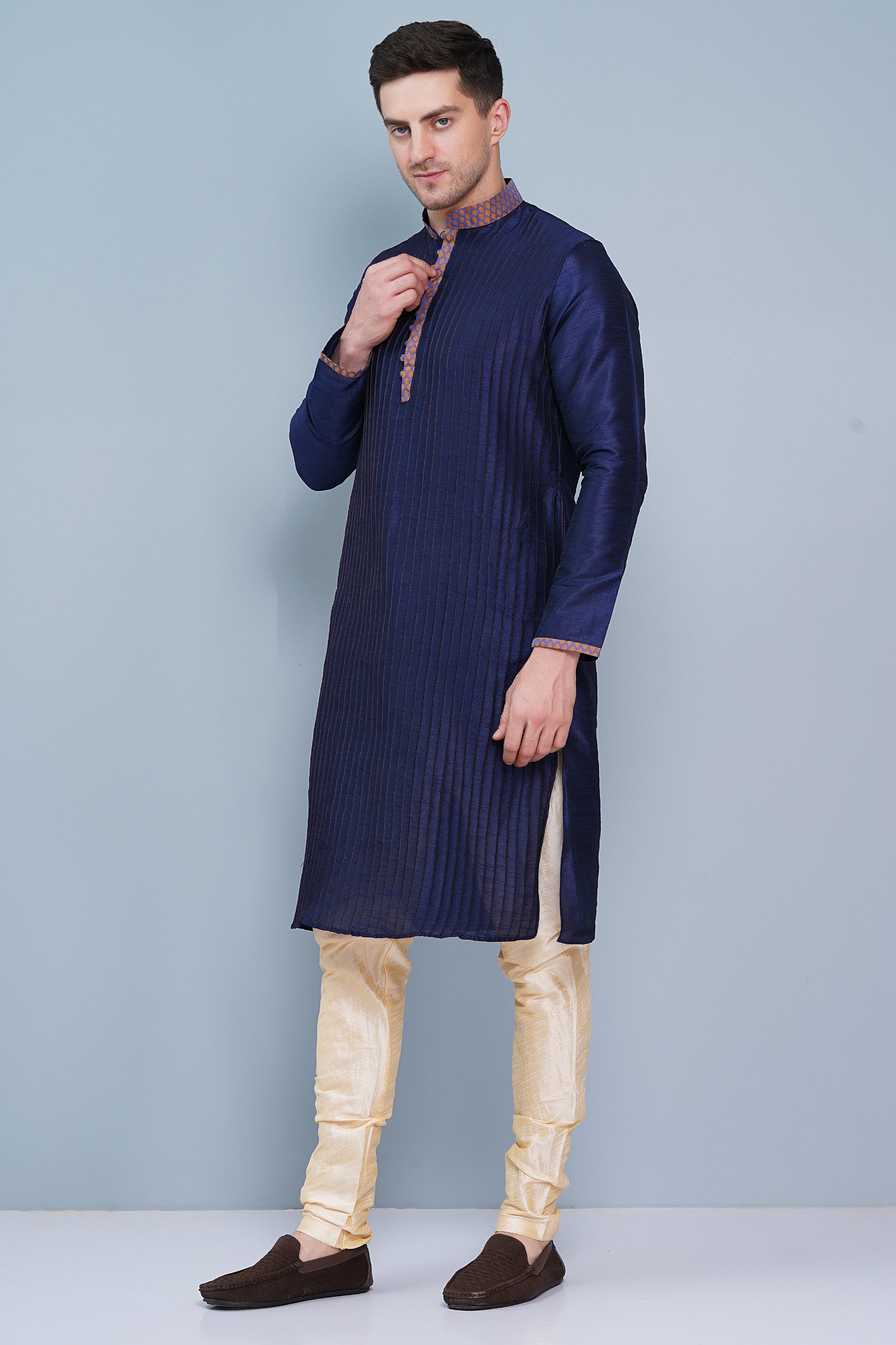 Men Navy Blue traditional Kurta with orange accent  on collar, placket and cuffs, full length, boondi button with loops closure, one fourth placket, full sleeves, mandarin collar, side pockets on Kurta with Off-white or cream color chudidar pajama. Perfect traditional wear for family special occasions, wedding, house warming, casual wear