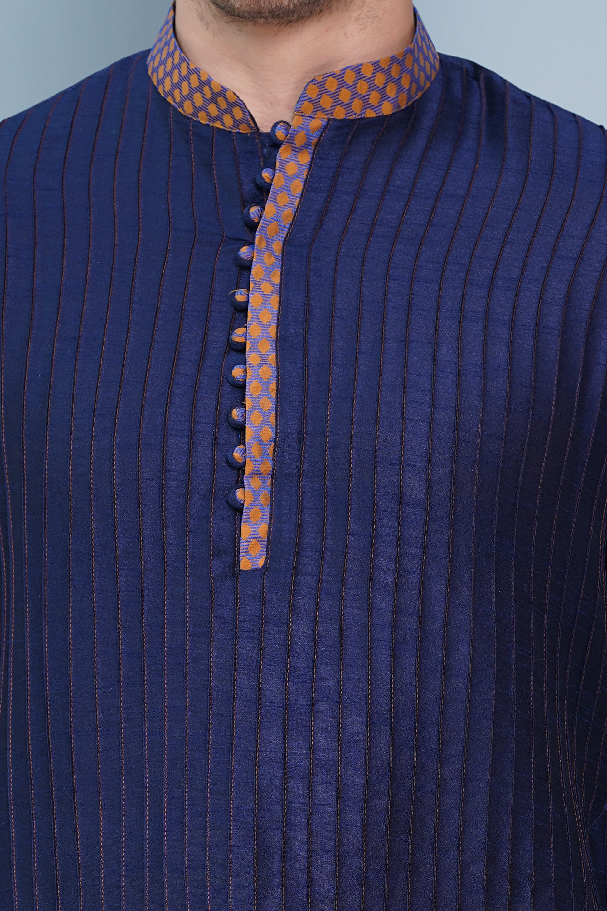 Men Navy Blue traditional Kurta with orange accent  on collar, placket and cuffs, full length, boondi button with loops closure, one fourth placket, full sleeves, mandarin collar, side pockets on Kurta with Off-white or cream color chudidar pajama. Perfect traditional wear for family special occasions, wedding, house warming, casual wear