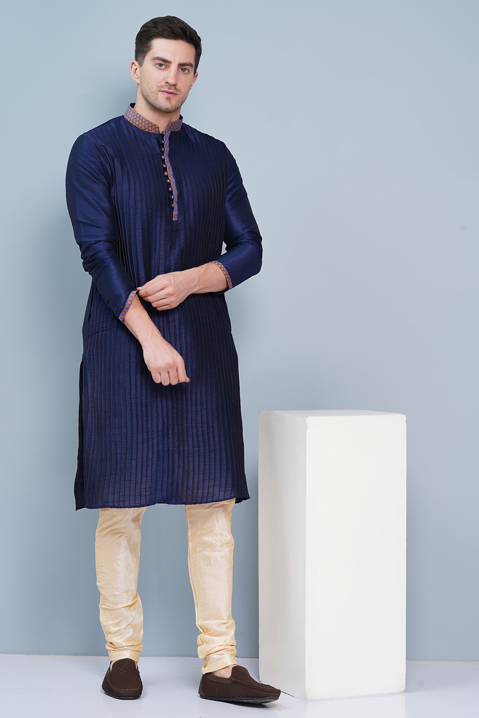 Men Navy Blue traditional Kurta with orange accent  on collar, placket and cuffs, full length, boondi button with loops closure, one fourth placket, full sleeves, mandarin collar, side pockets on Kurta with Off-white or cream color chudidar pajama. Perfect traditional wear for family special occasions, wedding, house warming, casual wear