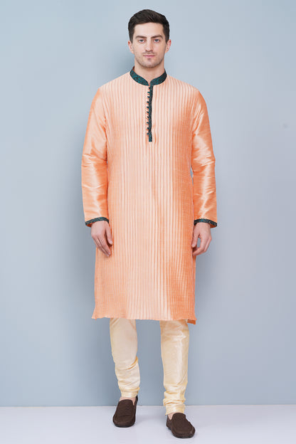 Men Peach color traditional Kurta with green accent  on collar, placket and cuffs, full length, boondi button with loops closure, one fourth placket, full sleeves, mandarin collar, side pockets on Kurta with Off-white or cream color chudidar pajama. Perfect traditional wear for family special occasions, wedding, house warming, casual wear