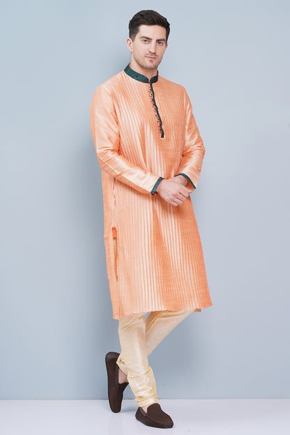Men Peach color traditional Kurta with green accent  on collar, placket and cuffs, full length, boondi button with loops closure, one fourth placket, full sleeves, mandarin collar, side pockets on Kurta with Off-white or cream color chudidar pajama. Perfect traditional wear for family special occasions, wedding, house warming, casual wear